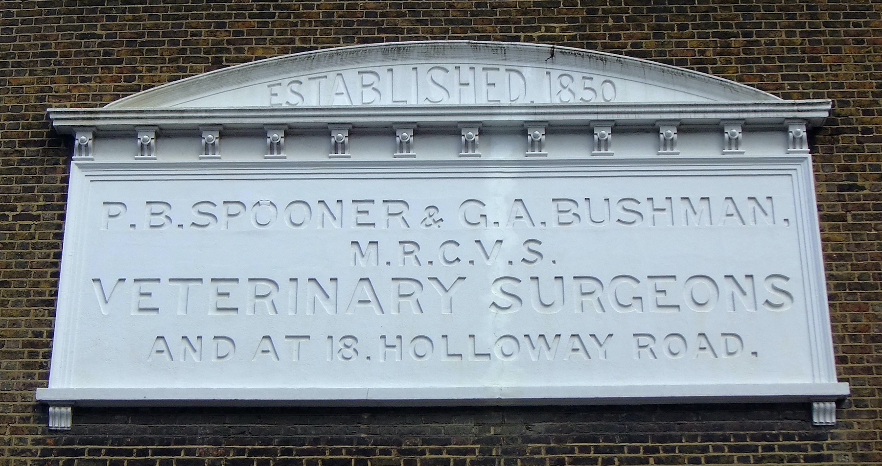 Old Spooner and Bushman Veterinary Surgeons stone plaque on a wall, Islington. Sidney Ray